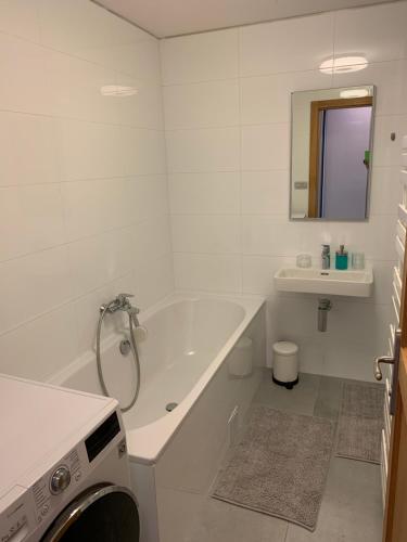a white bathroom with a tub and a sink at Apartment Grossman in Hradec Králové