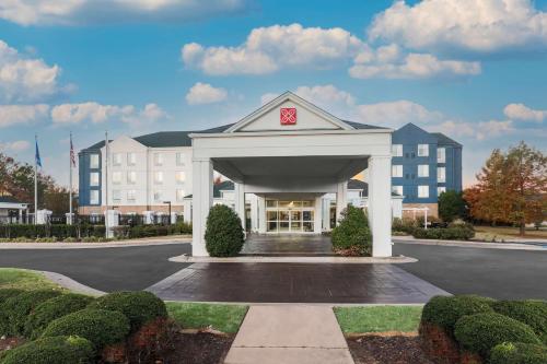 a large white building with a gate in a parking lot at Hilton Garden Inn Tulsa South in Tulsa