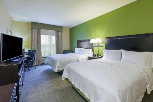 a hotel room with two beds and a flat screen tv at Hampton Inn & Suites Owasso in Owasso