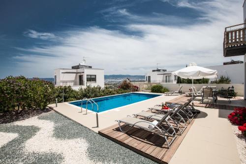 a swimming pool with lounge chairs next to a house at Jenny Villa 23 in Polis Chrysochous