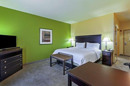 a hotel room with a bed and a flat screen tv at Hampton Inn & Suites Owasso in Owasso