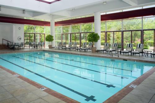 una gran piscina con sillas, mesas y ventanas en DoubleTree by Hilton Tulsa at Warren Place, en Tulsa