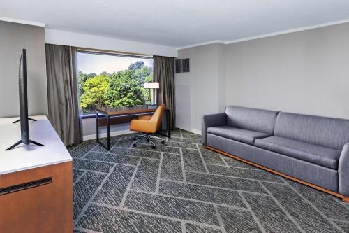 a living room with a couch and a desk at DoubleTree by Hilton Tulsa - Warren Place in Tulsa