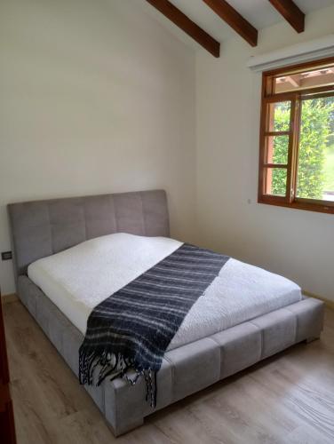 uma cama num quarto branco com uma janela em Habitación tranquila en casa campestre em Pereira
