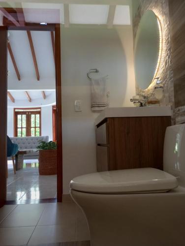 uma casa de banho com um WC, um lavatório e um espelho. em Habitación tranquila en casa campestre em Pereira