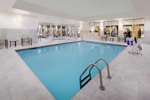a large pool in a hotel with tables and chairs at Hilton Garden Inn Tyler in Tyler