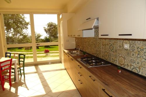 eine Küche mit einem Herd, einem Tisch und einem Fenster in der Unterkunft B&B Nucria - Nocera Terinese in Nocera Terinese