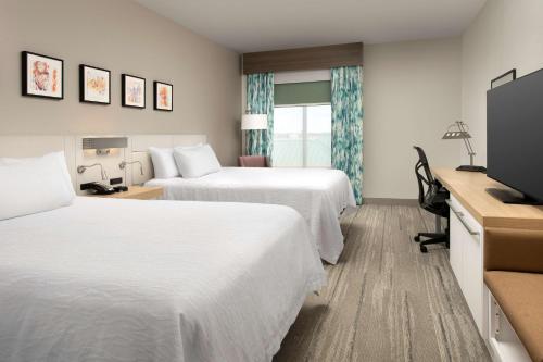 a hotel room with two beds and a flat screen tv at Hilton Garden Inn Knoxville West/Cedar Bluff in Knoxville