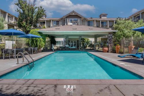 a swimming pool with chairs and umbrellas in front of a house at Hampton Inn Ukiah in Ukiah