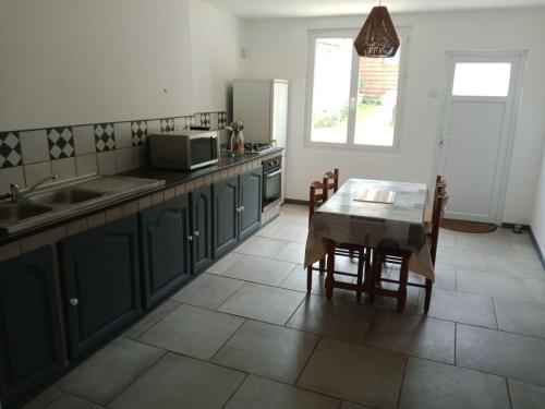 une cuisine avec des placards verts et une table avec des chaises dans l'établissement LES PIEDS DANS L'EAU, à Fécamp