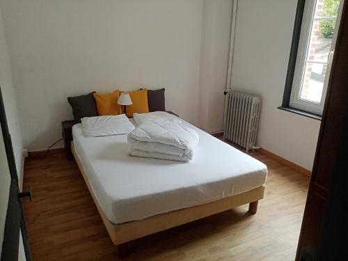 un lit avec des draps blancs et des oreillers dans une chambre dans l'établissement LES PIEDS DANS L'EAU, à Fécamp