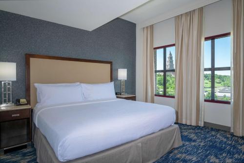 a large bed in a hotel room with windows at Embassy Suites by Hilton Alexandria Old Town in Alexandria