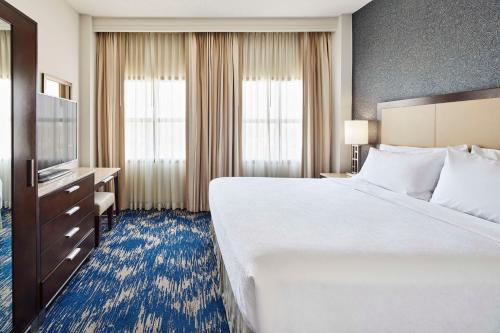 a hotel room with a large bed and a television at Embassy Suites by Hilton Alexandria Old Town in Alexandria