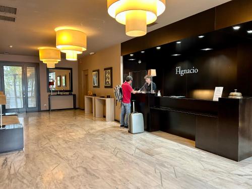 a man with a suitcase standing at a hotel counter at Hotel Ignacio - PalomarGroup in Chiva