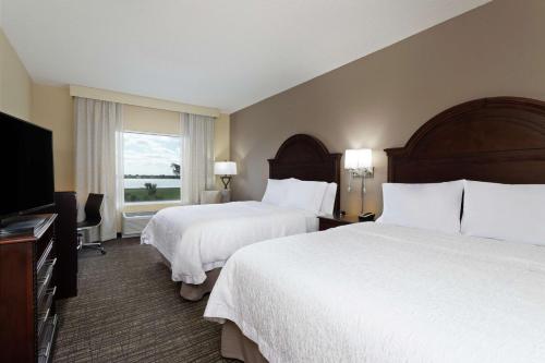 a hotel room with two beds and a flat screen tv at Hampton Inn & Suites Wellington in Wellington