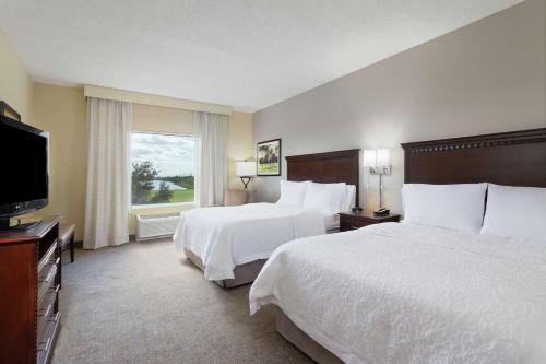 a hotel room with two beds and a flat screen tv at Hampton Inn & Suites Wellington in Wellington