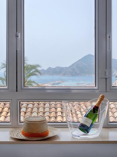 a bottle of wine and a hat on a table in front of a window at Hostal Perla Blanca Altea in Altea