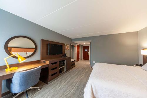 a hotel room with a bed and a desk and a mirror at Hampton Inn Winchester in Winchester