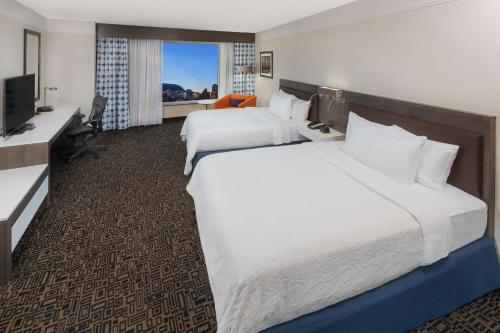a hotel room with two beds and a desk at Hilton Garden Inn Montreal Centre-Ville in Montreal