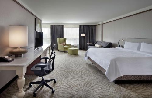 a hotel room with a bed and a desk with a television at Hilton Garden Inn Montreal Airport in Dorval