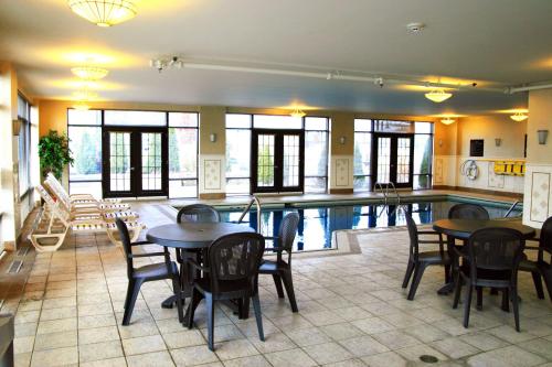 a pool room with tables and chairs and a swimming pool at Hampton Inn & Suites Laval in Laval