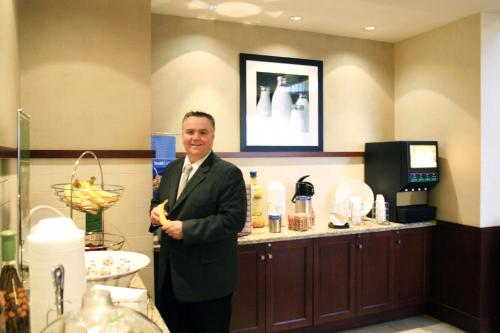 a man standing in a bathroom with a counter at Hampton Inn & Suites Laval in Laval