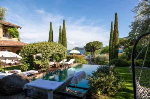 a pool in a garden with chairs and trees at La Criolda Charming Villa in San Felice del Benaco