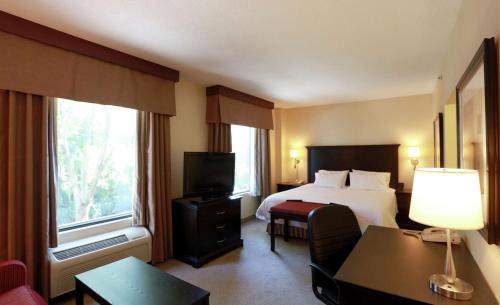 a hotel room with a bed and a desk and a television at Hampton Inn & Suites Laval in Laval