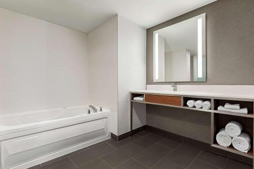 Hilton Garden Inn Kitchener/Cambridge في كامبريدج: حمام مع حوض ومغسلة ومرآة