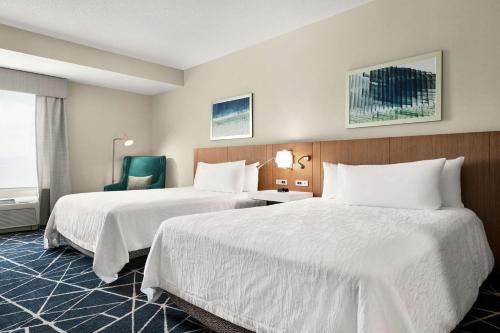 um quarto de hotel com duas camas e uma cadeira em Hilton Garden Inn Kitchener/Cambridge em Cambridge