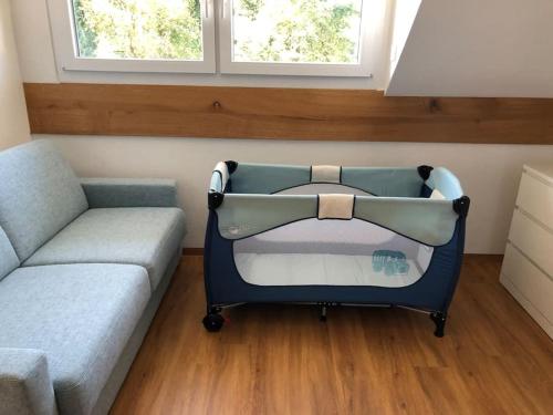 a baby crib in a room with a couch and window at Neue luxuriöse Ferienwohnung in ruhiger Lage in Leutkirch im Allgäu