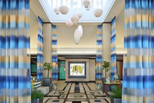 a lobby with blue and yellow walls and a hallway with palm trees at Hilton Garden Inn Toronto Airport West/Mississauga in Mississauga