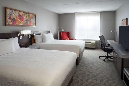 a hotel room with two beds and a desk at Hilton Garden Inn Toronto Airport West/Mississauga in Mississauga