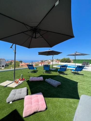 a group of umbrellas and lounge chairs and a pool at Villa La Vie - Podstrana in Podstrana