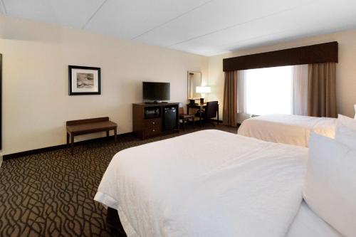a hotel room with two beds and a desk at Hampton Inn Butler in Butler
