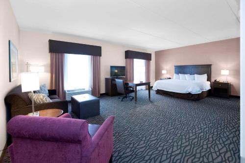 a hotel room with a bed and a couch and chair at Hampton Inn Butler in Butler