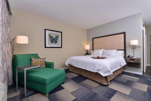 BroussardにあるHampton Inn Broussard-Lafayetteのベッドと緑の椅子が備わるホテルルームです。