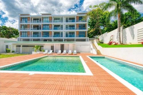 a swimming pool in front of a building at Apt 6ix - Modern and Airy @ Paradise Bay in Montego Bay
