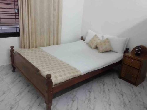 a bed in a room with a nightstand and a bed with white sheets at *NEW BUILD* Luxury Holiday Home in Sylhet