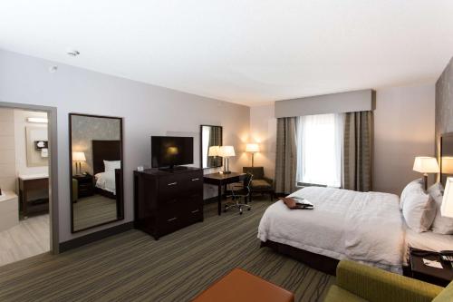 ein Hotelzimmer mit einem Bett und einem Spiegel in der Unterkunft Hampton Inn by Hilton Lloydminster in Lloydminster