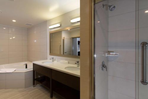 a bathroom with a sink and a mirror and a shower at Hampton Inn by Hilton Lloydminster in Lloydminster