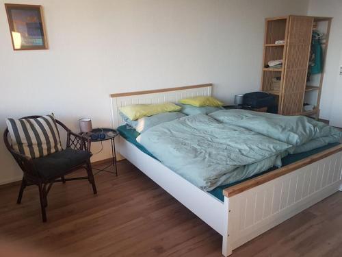 a bedroom with a large bed and a chair at Ferienwohnung `Ton Utkiek` in Bremerhaven
