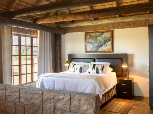 1 dormitorio con 1 cama grande con sábanas y almohadas blancas en Linglela Lodge, en Estcourt