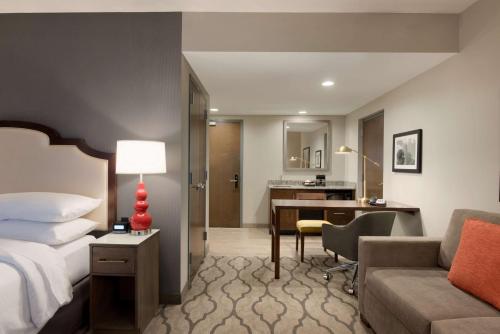 a hotel room with a bed and a desk at Embassy Suites by Hilton Chicago Naperville in Naperville
