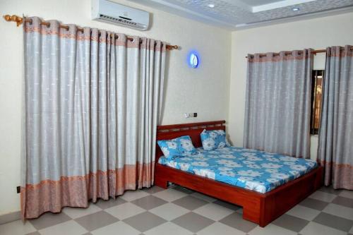 a small bedroom with a bed with curtains at Residence Patricia in Cotonou