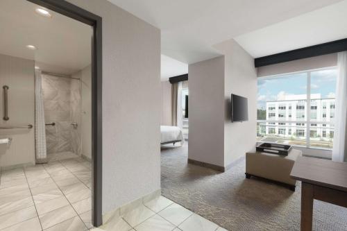 a bathroom with a large glass door leading to a bedroom at Embassy Suites Charlotte/Ayrsley in Charlotte