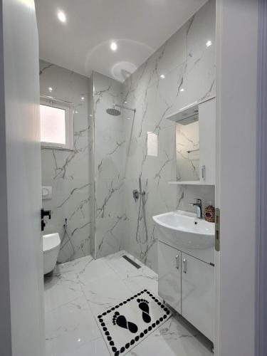 a white bathroom with a sink and a mirror at Luxury Room's by Lika in Sarandë