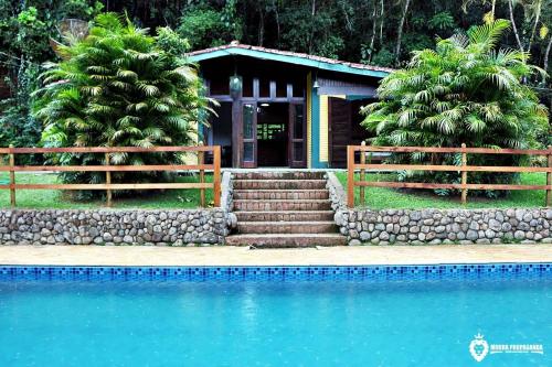 a house with a swimming pool in front of a house at Eco Chalés Luar das Marés in Ubatuba