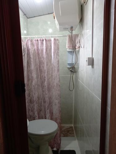 y baño con aseo y cortina de ducha. en Habitación Independiente, en Chuy