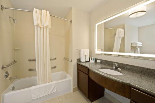La salle de bains est pourvue d'une baignoire, d'un lavabo et d'un miroir. dans l'établissement Homewood Suites by Hilton Denver West - Lakewood, à Lakewood